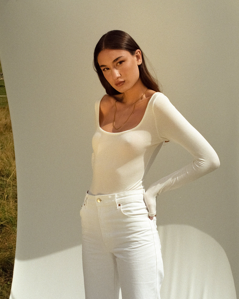 Woman modeling front of white Collagen Back Ribbon Bodysuit