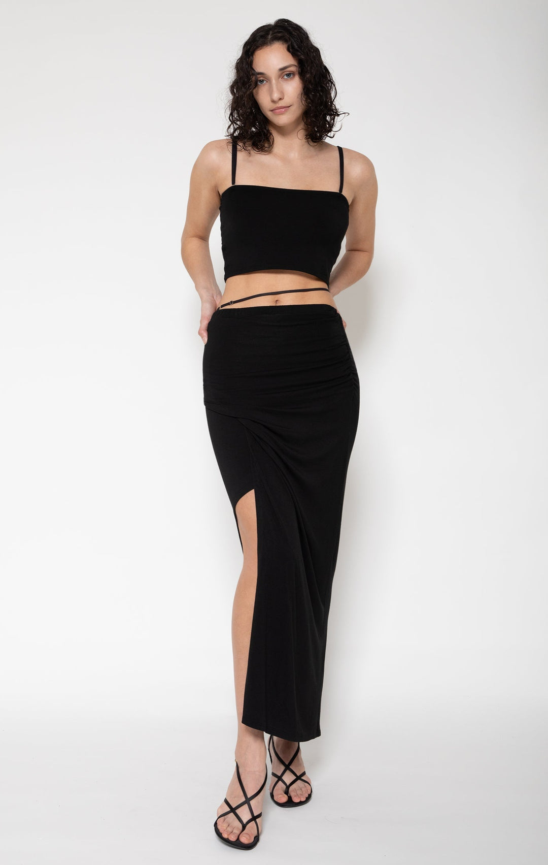 Woman modeling front of the black"Collagen Wrap Slit Skirt"