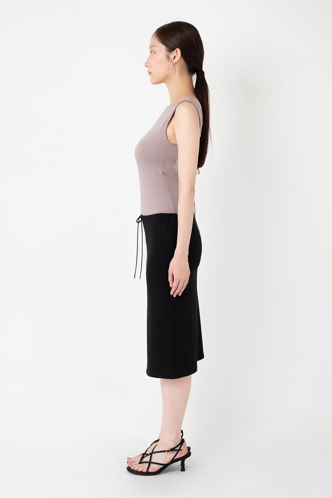 Woman modeling front of the black”Collagen Midi Skirt"