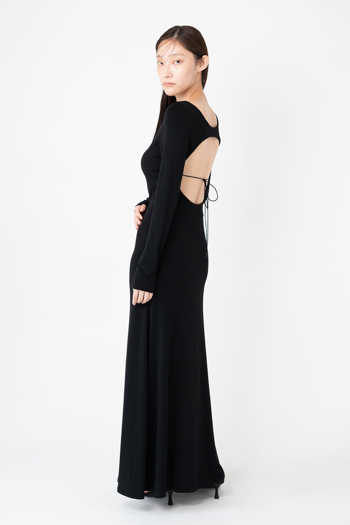 Woman modeling front of the black "Collagen Open Back Dress"