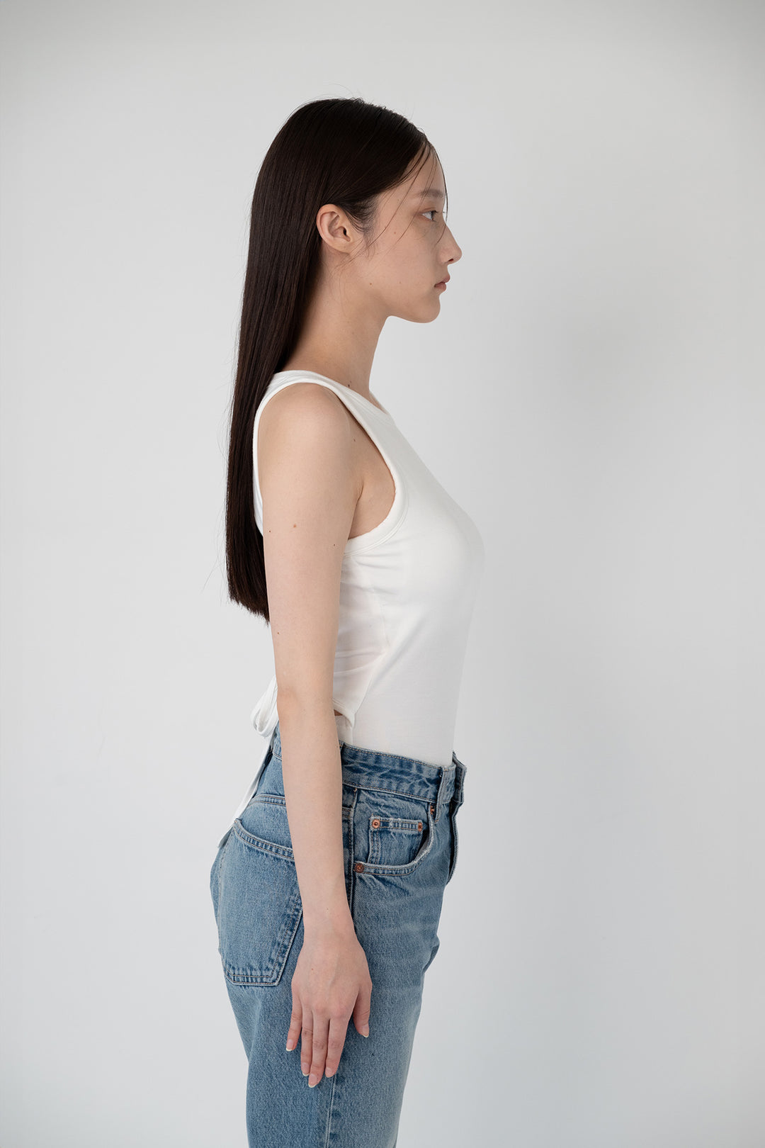 Woman modeling front of the white "Collagen Tie Back Bodysuit"