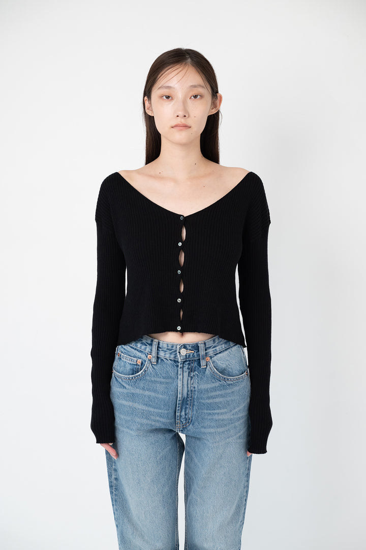 Woman modeling front of the black "back ribbon short cardigan"